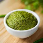 Homemade Thai green curry paste in a bowl with fresh herbs and spices